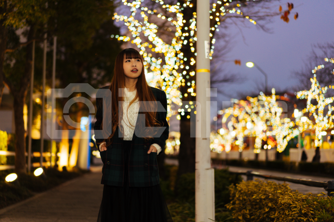 横浜のイルミネーションを背景に歩道を歩く女性